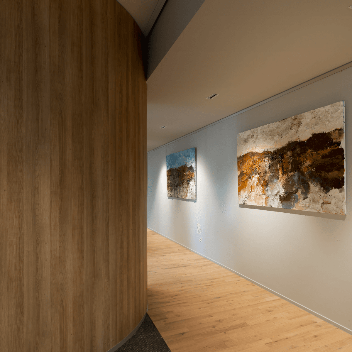 Gang met houten vloer en twee kunstschilderijen HVK Stevens