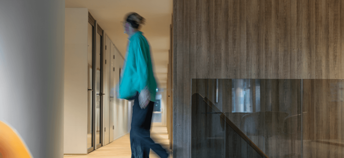 Persoon in groene trui loopt door gang met glazen wanden HVK Stevens
