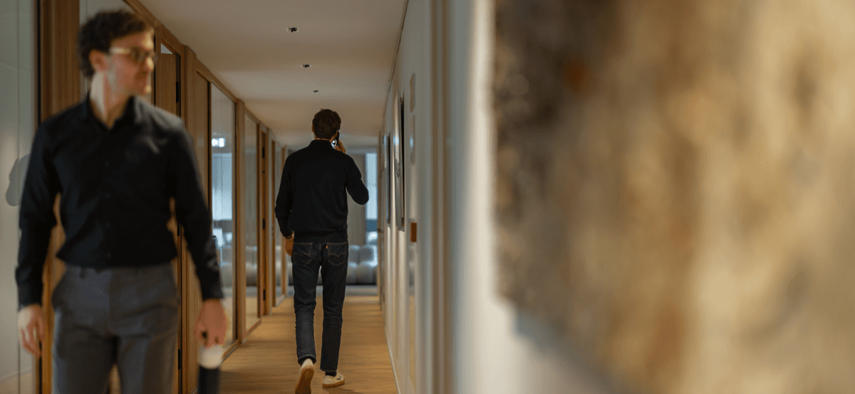 two men in office hallway one on the phone and one with coffee cup hvk stevens