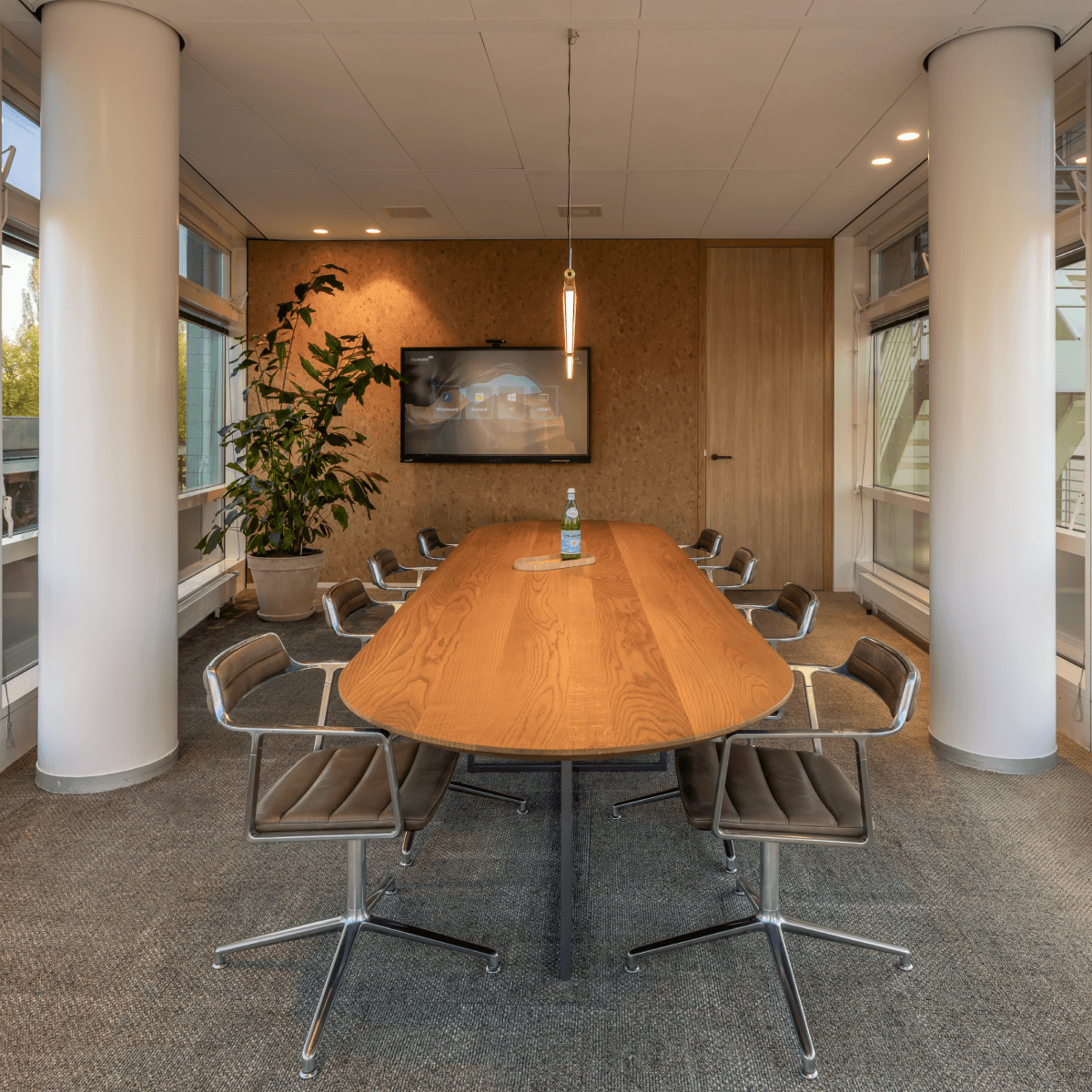 Vergaderruimte met houten tafel en plant HVK Stevens