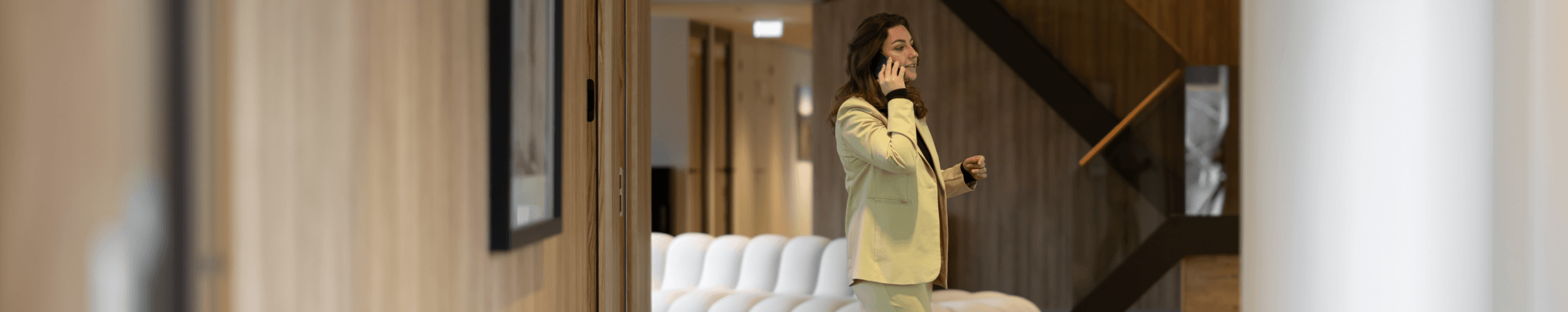 Vrouw in lichtgroen pak wandelt en telefoneert in kantoor hvk stevens