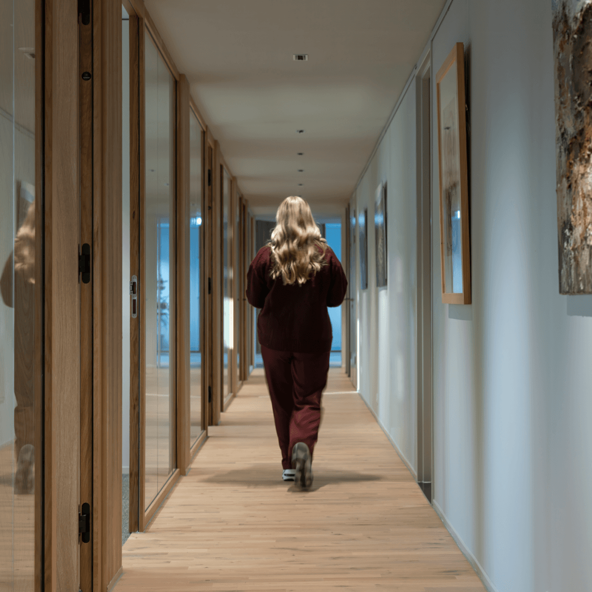 Vrouw met lang blond haar in gang met houten vloer HVK Stevens