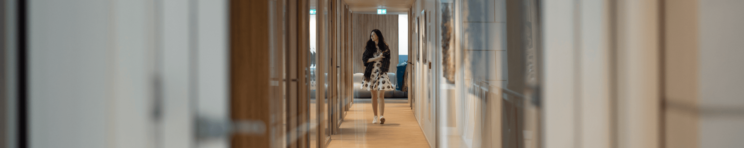 Woman with notepad walking through office hallway with wooden floor HVK Stevens