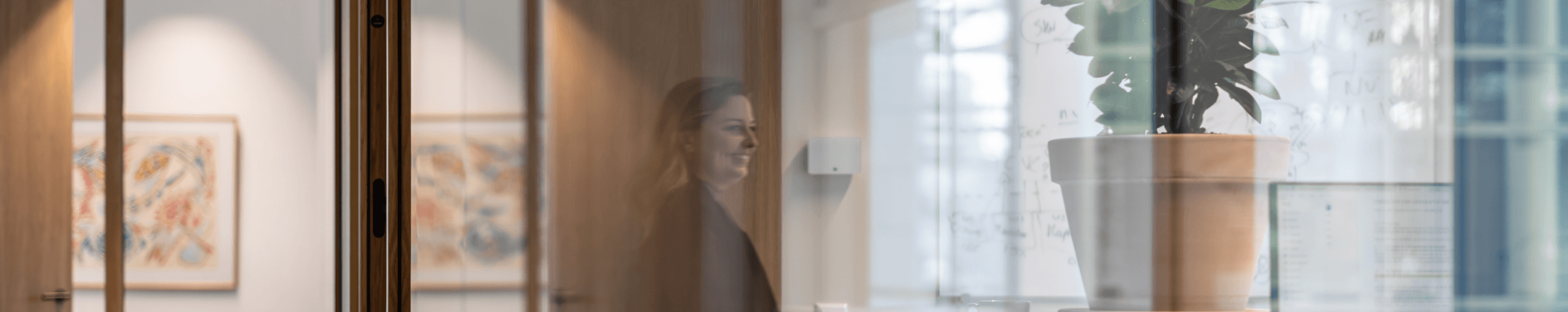 Vrouw zichtbaar via reflectie naast whiteboard en plant HVK Stevens