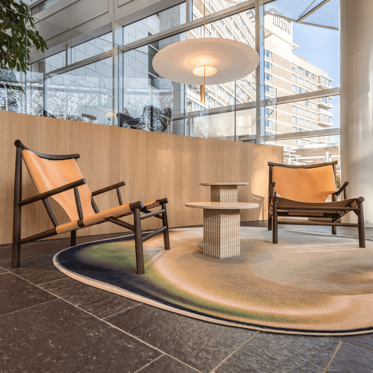 Zitruimte met leren stoelen en rond vloerkleed HVK Stevens