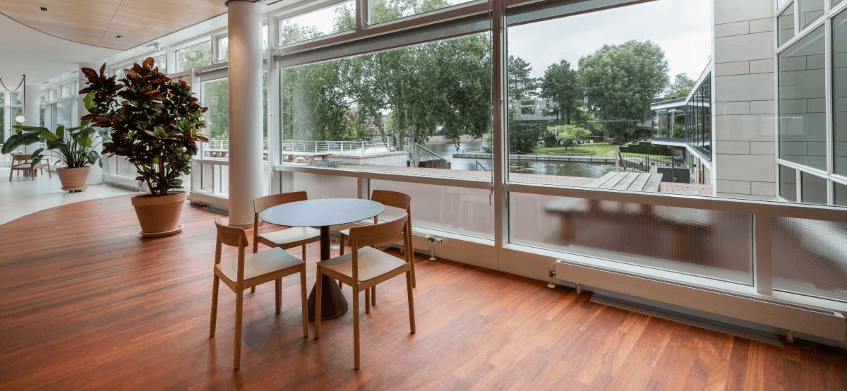 Kleine ronde tafel met houten stoelen naast groot raam met uitzicht op water hvk stevens