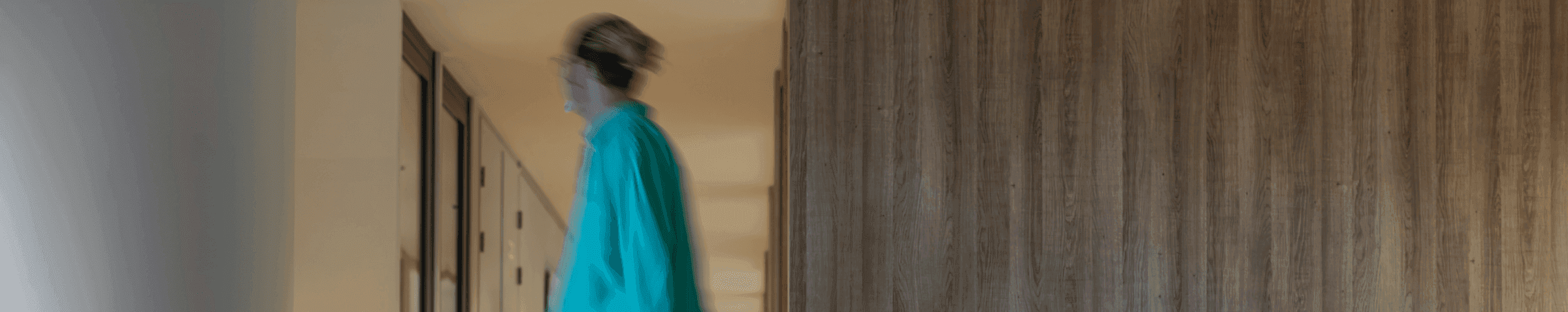 Persoon in groene trui loopt door gang met glazen wanden