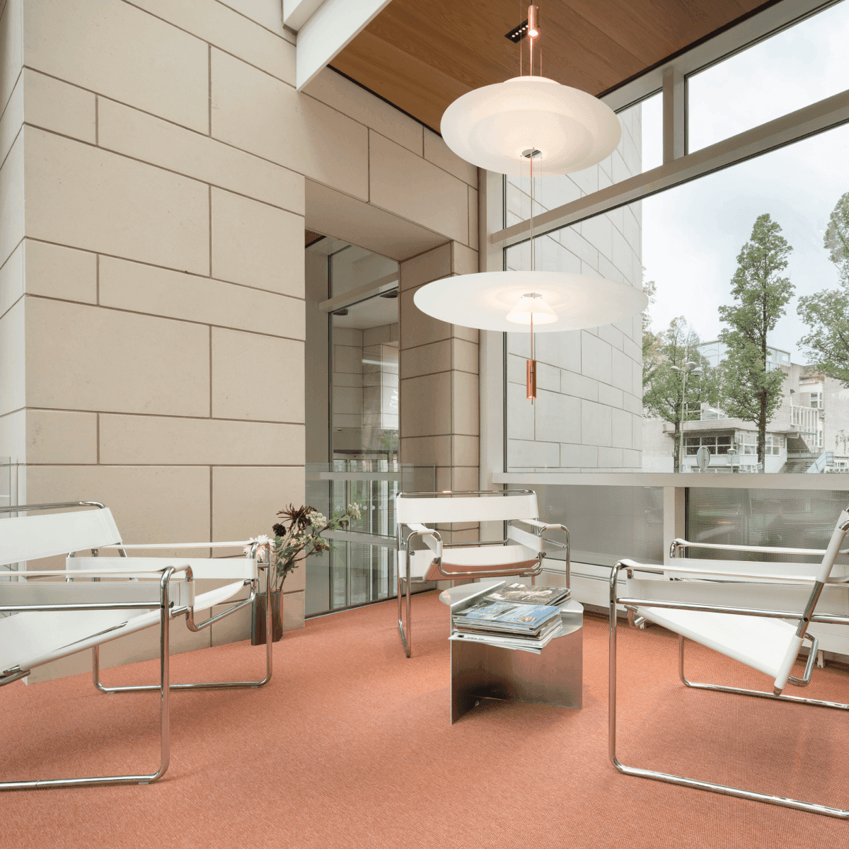 Zithoek met witte stoelen en oranje vloer in kantoorruimte